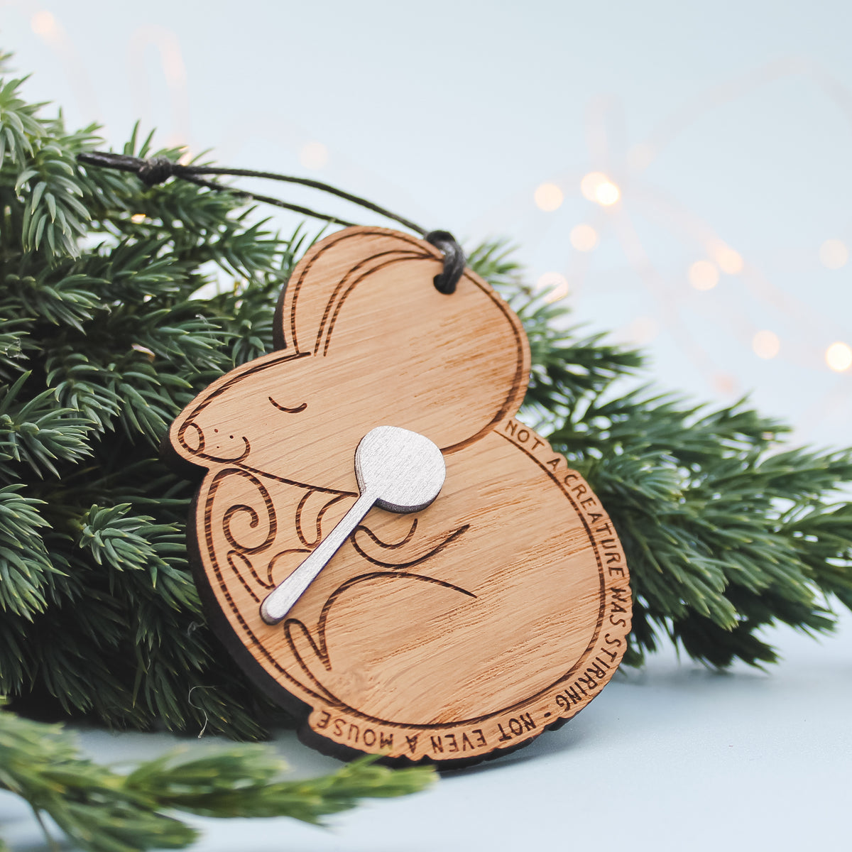 Wooden ornament, sleeping mouse holding a silver spoon on a Christmas tree branch.
