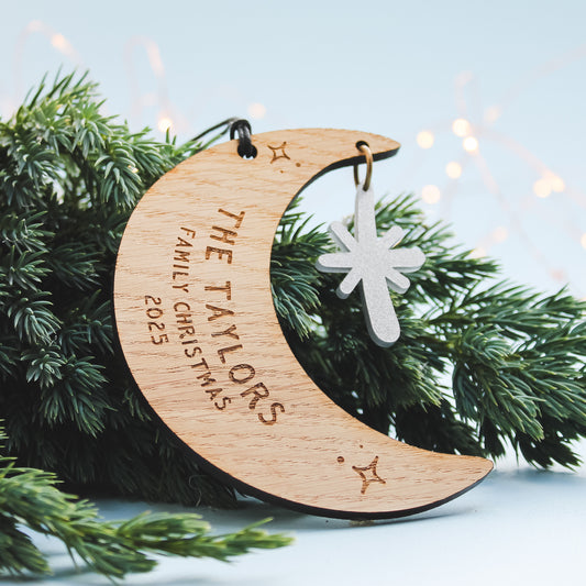 Wooden crescent moon ornament with personalised newlywed couple surname  engraved. Sitting on a Christmas tree.