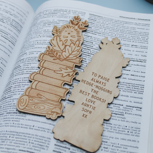 Wooden hedgehog bookmark with personalised engraved text laying on an open book