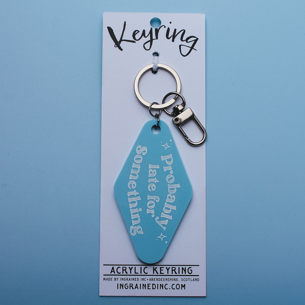 Blue motel style keychain with text saying 'probably late for something' on a white backing card against a blue background