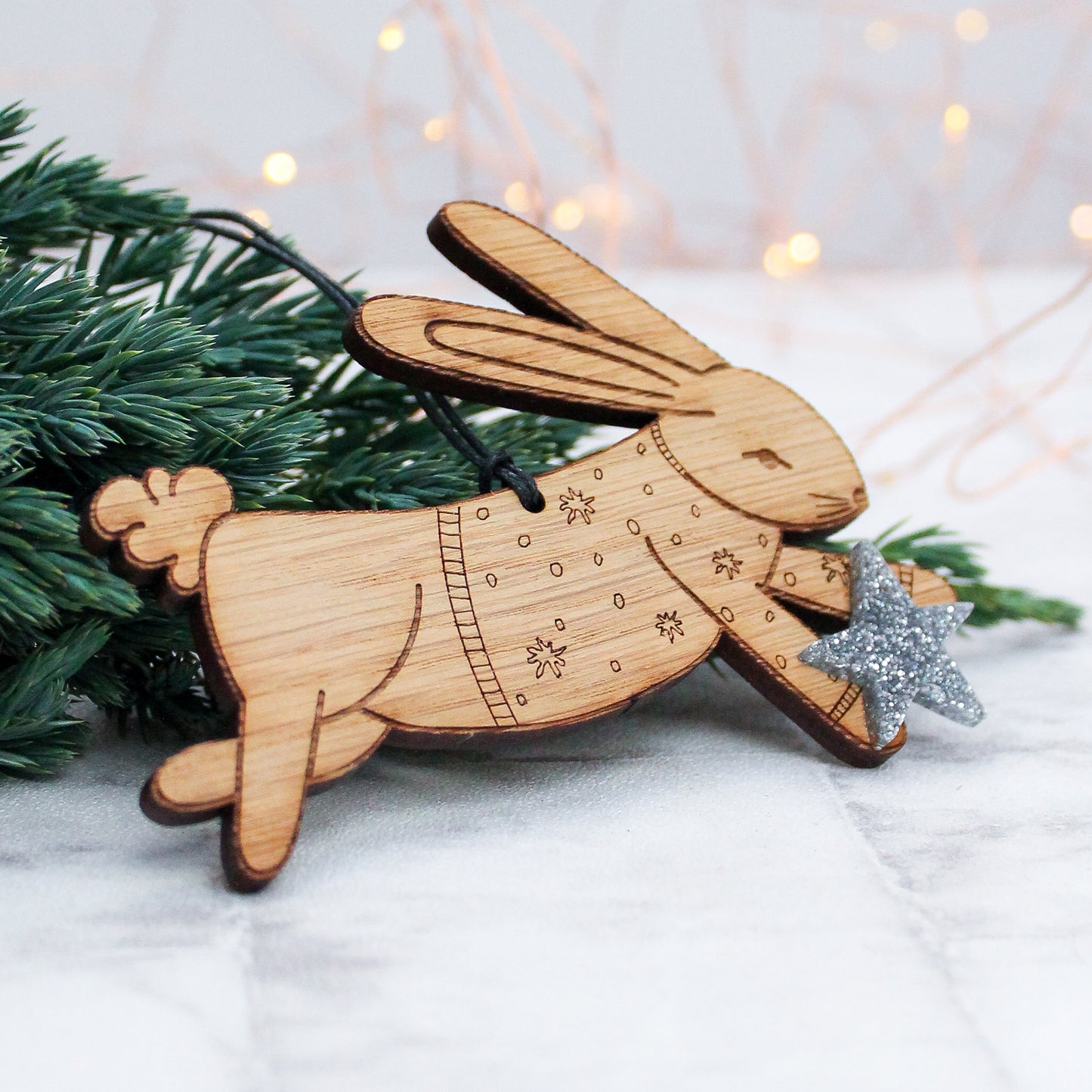 wooden bunny rabbit Christmas tree decoration in winter jumper and holding a silver star