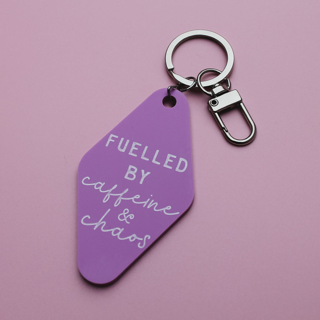 Pink motel style keychain with 'Fuelled by caffeine & chaos' text on a pink background