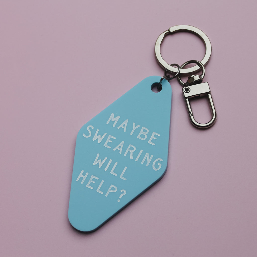 Blue motel style keyring tag with text 'MAYBE SWEARING WILL HELP?' on a pink background