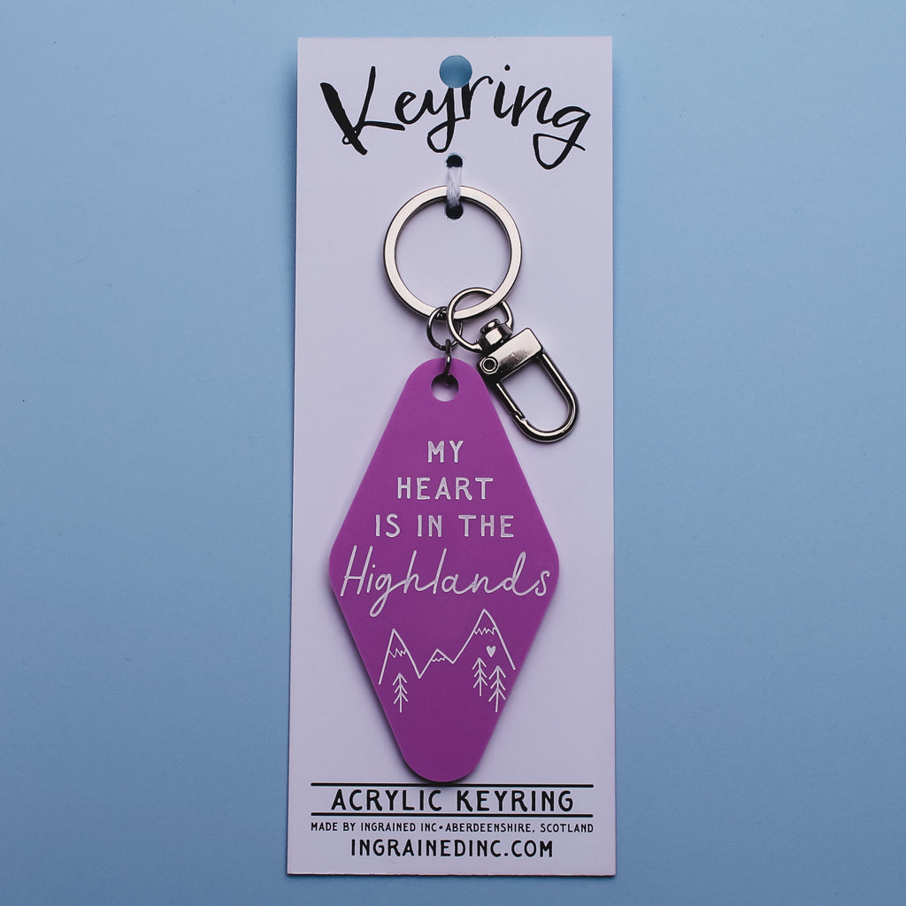 Pink motel style keychain with 'My heart is in the Highlands' text on a white backing card against a blue background