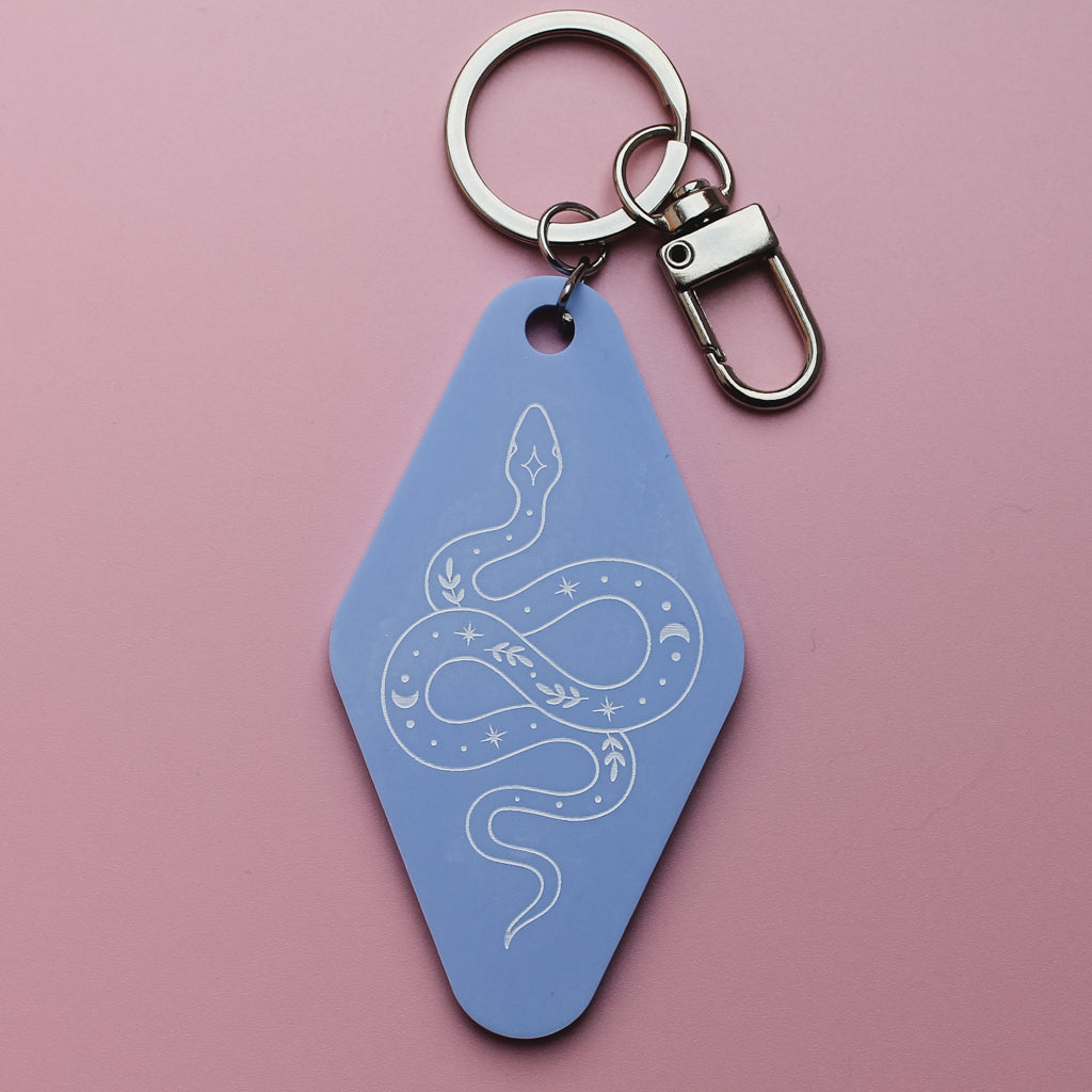 Blue motel style keychain with a snake design on a pink background