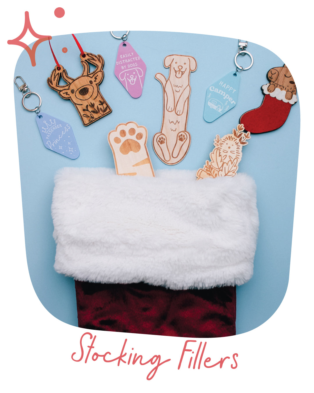A set of Christmas stocking fillers displayed inside a white faux-fur stocking with a red velvet cuff, set against a light blue background with decorative text reading 'Stocking Fillers'. The fillers include laser-engraved wooden shapes of a deer, a dog, a paw print, and a Christmas stocking, along with acrylic tags.