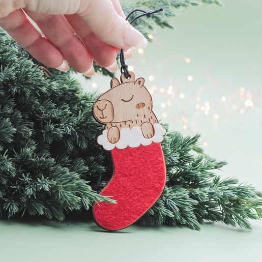 Wooden capybara in a Christmas stocking tree decoration, a quirky festive ornament and gift for capybara lovers.