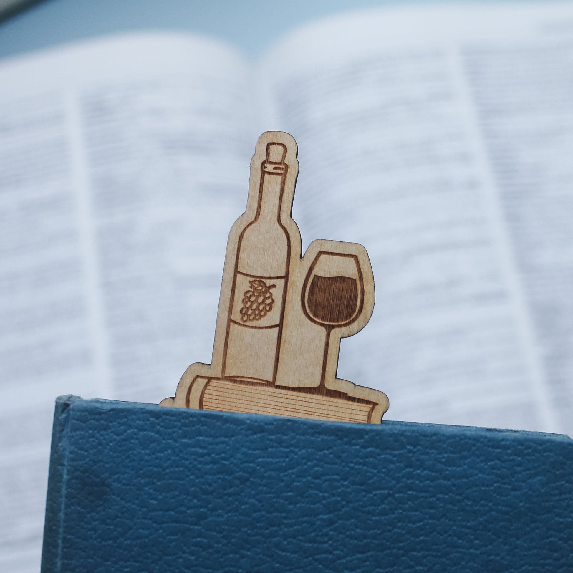 Wooden wine bottle bookmark peeking out of the top of a closed book