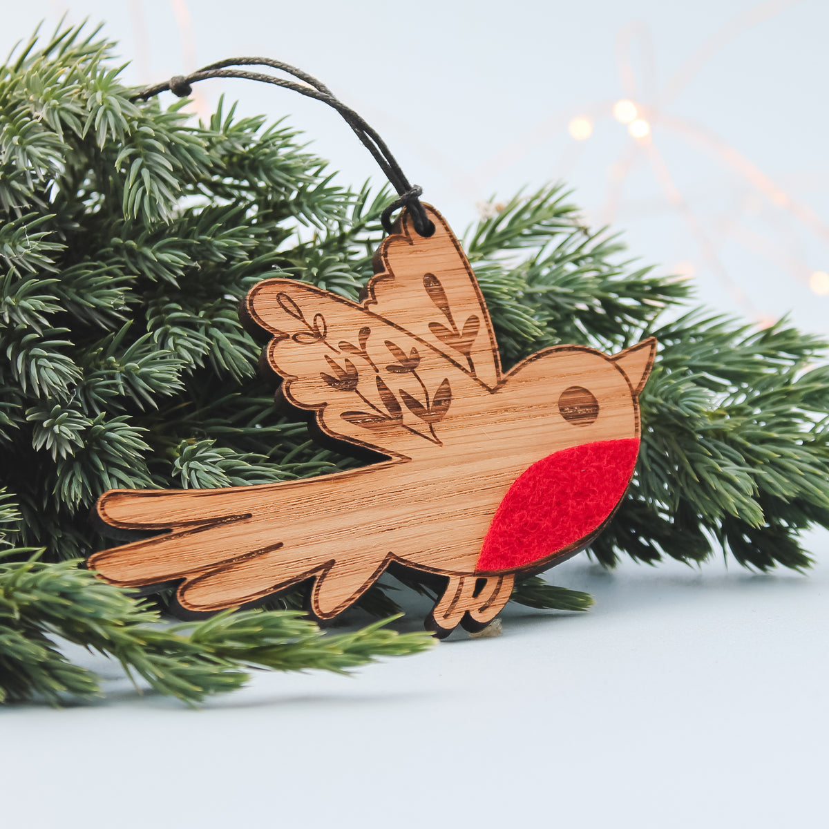 Wooden robin christmas ornament with red breast on a branch with lights in the background