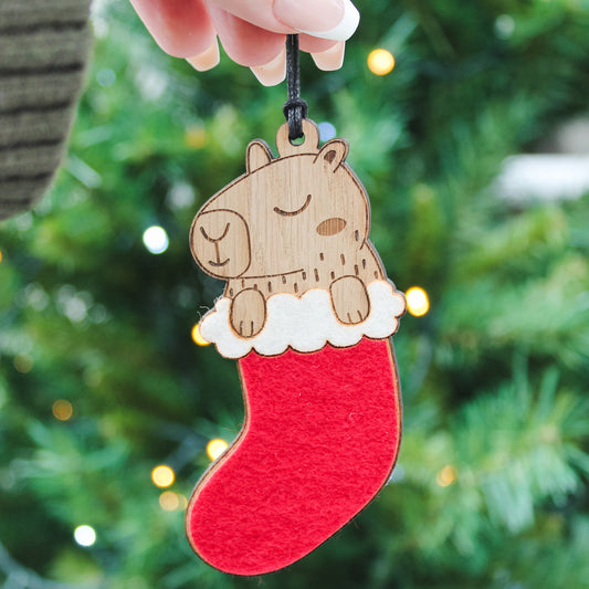Christmas capybara sitting in a Xmas stocking, a quirky festive ornament and gift for capybara lovers.