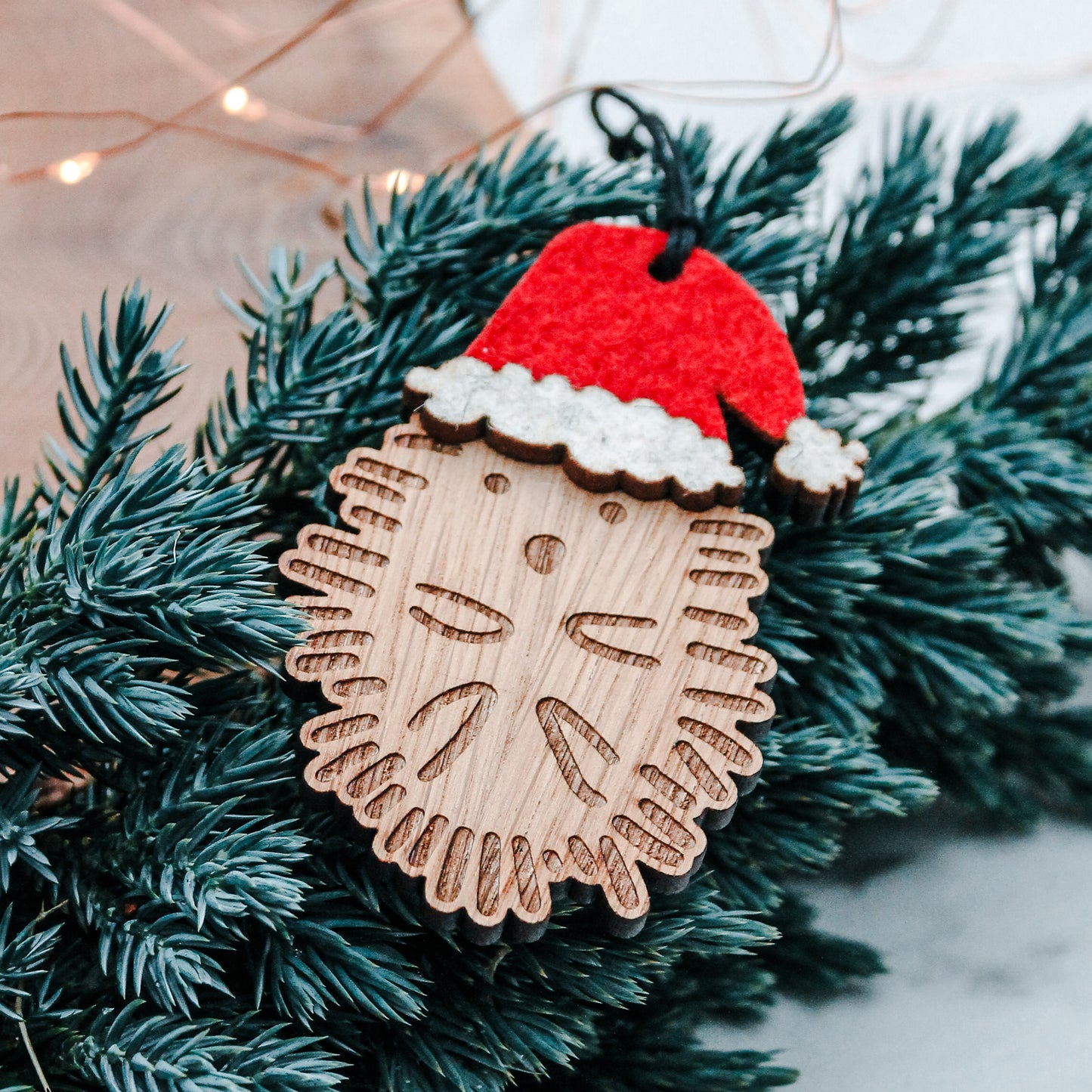 Wooden hedgehog Christmas tree decoration in felt Santa hat sitting in a Christmas tree branch  