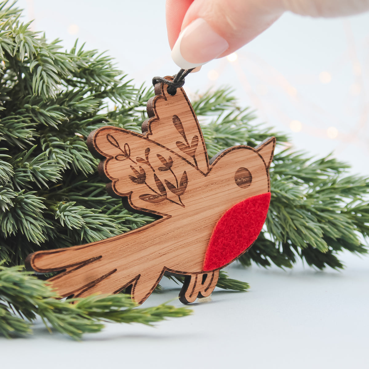 Wooden robin ornament with a red breast on a Christmas tree branch.
