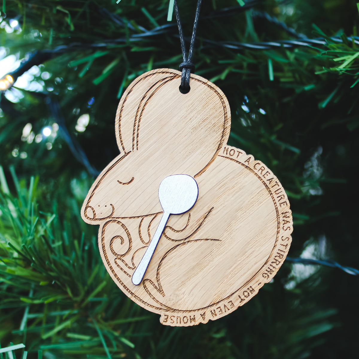 Wooden ornament shaped like a mouse with a spoon, hanging on a Christmas tree.