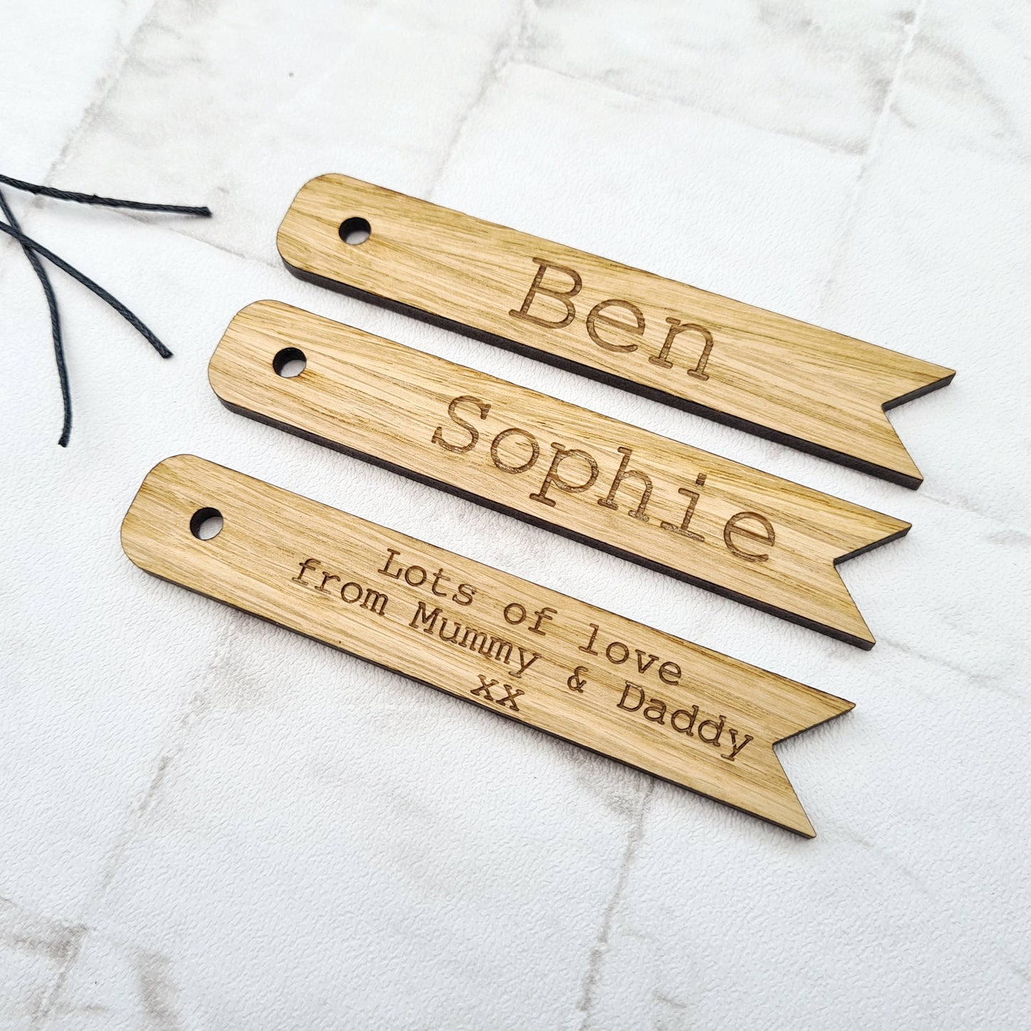 Personalised gift tags made from wood, engraved with custom names and attached with cotton string