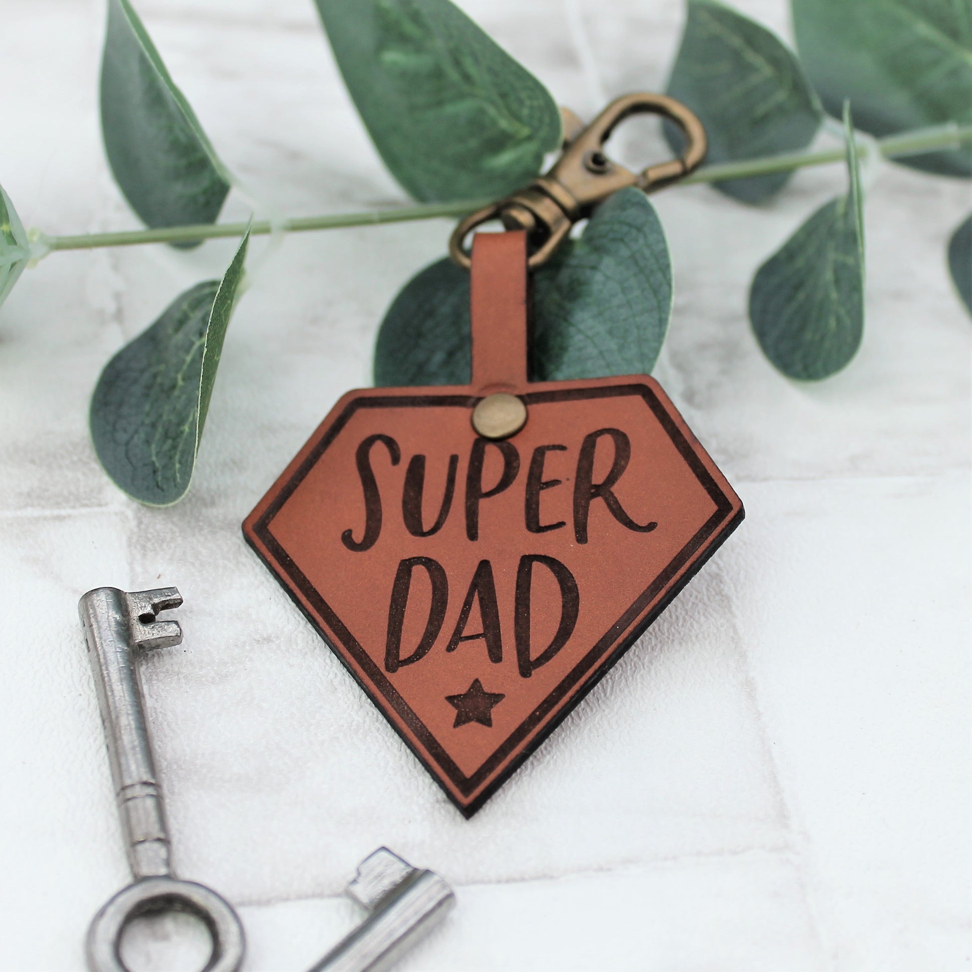 Engraved leather keyring with the text super dad on it in a super hero design