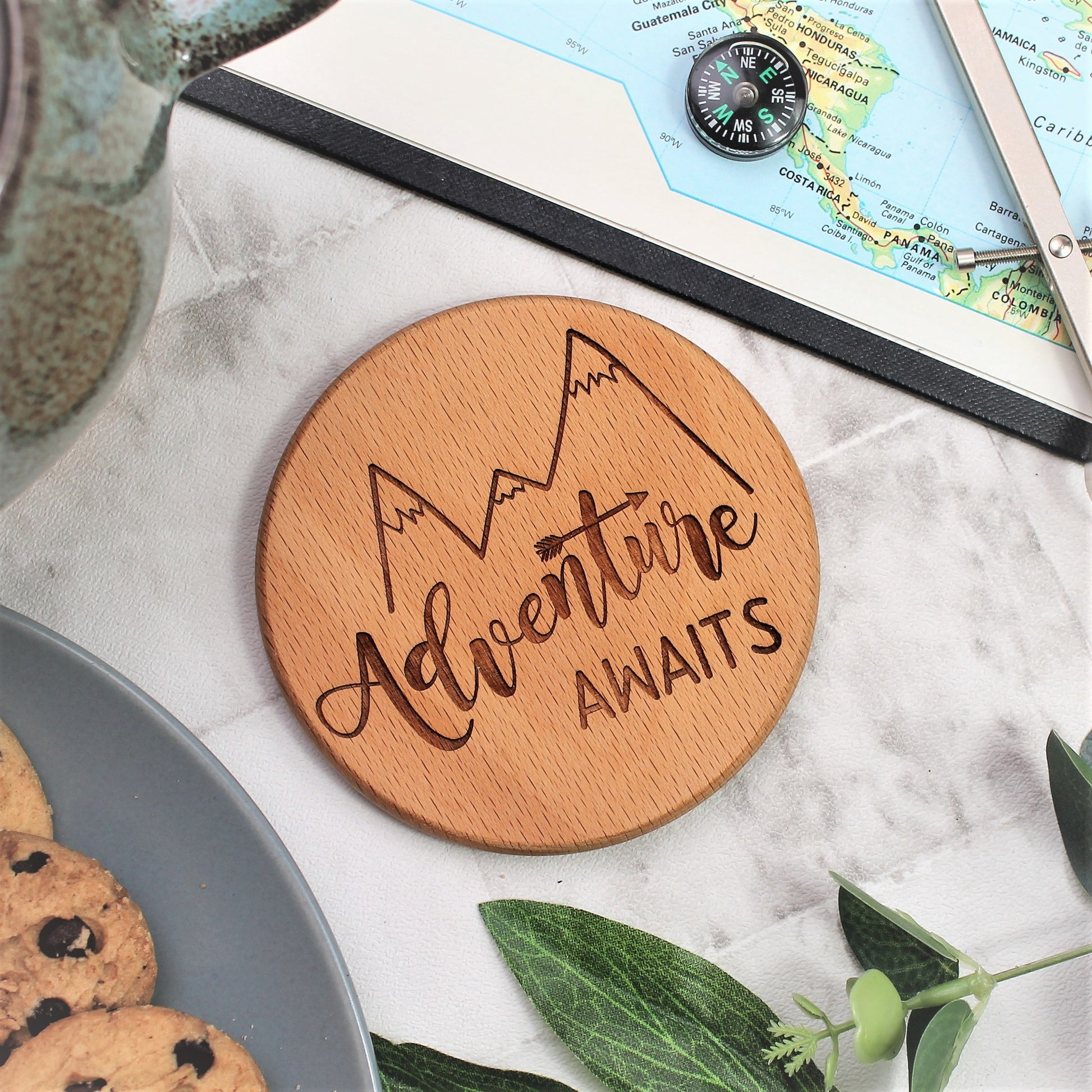 round engraved wooden coaster with the text engraved adventure awaits and a mountain design 