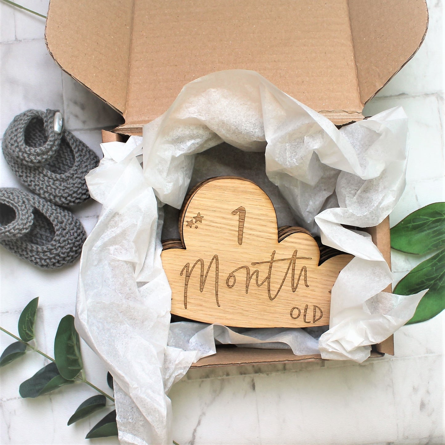 Packaged up baby milestone gift, in brown paper box and white tissue paper