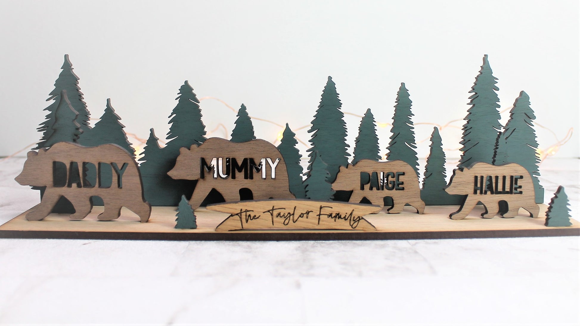 family personalised bears with names cut out. With a forest background with trees and a sign with your own surname on 