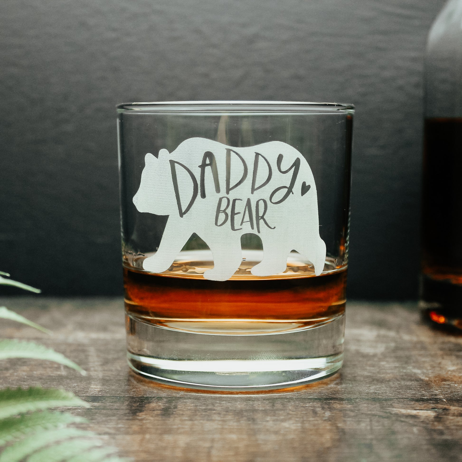 glass tumbler with white engraved bear with the words daddy bear engraved onto it with a short of whisky in the glass 