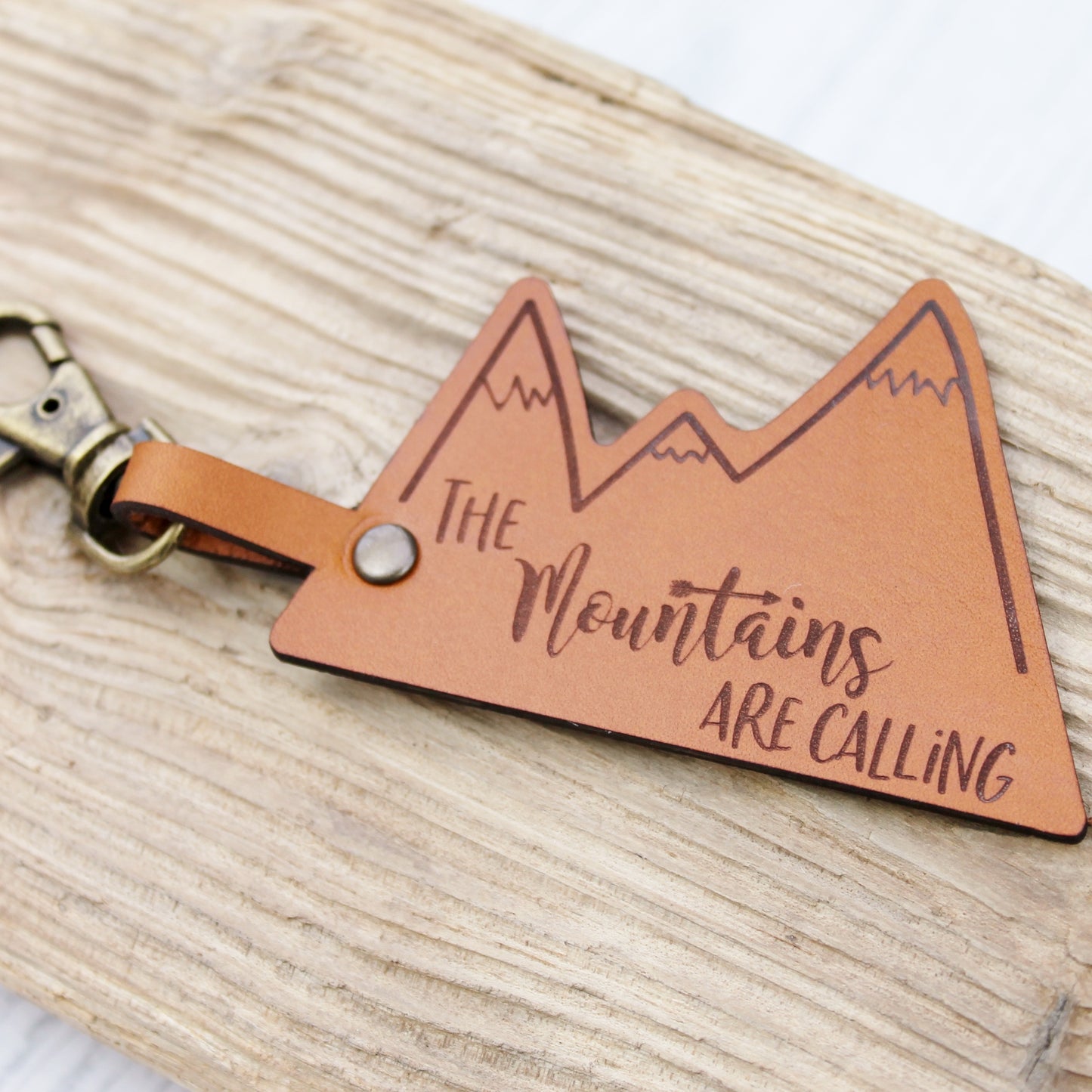 Leather keyring with the text engraved the mountains are calling with a mountain design 