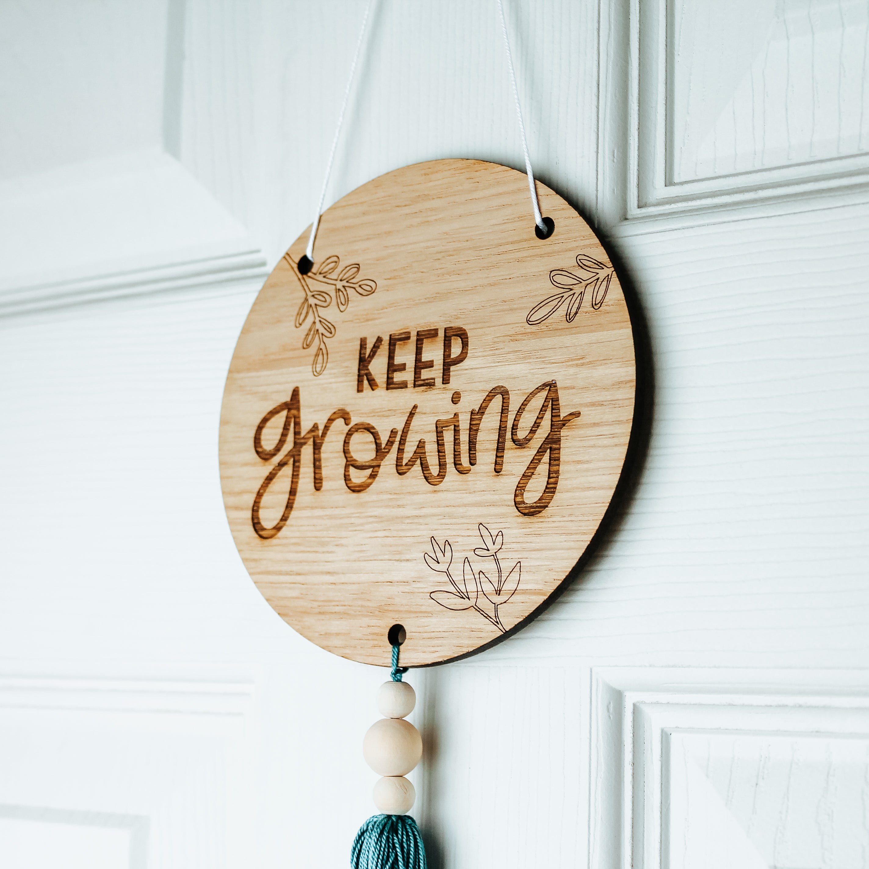 motivational wooden round sign for the plant lover. engraved with the phrase keep growing and botanical designs on it