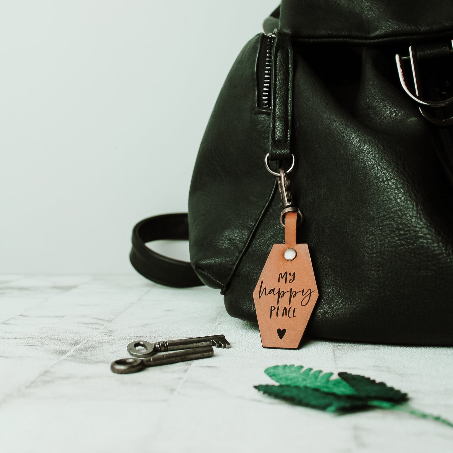 my happy place bag clasp made from real leather attached to a black bag with a swivel keyring clasp