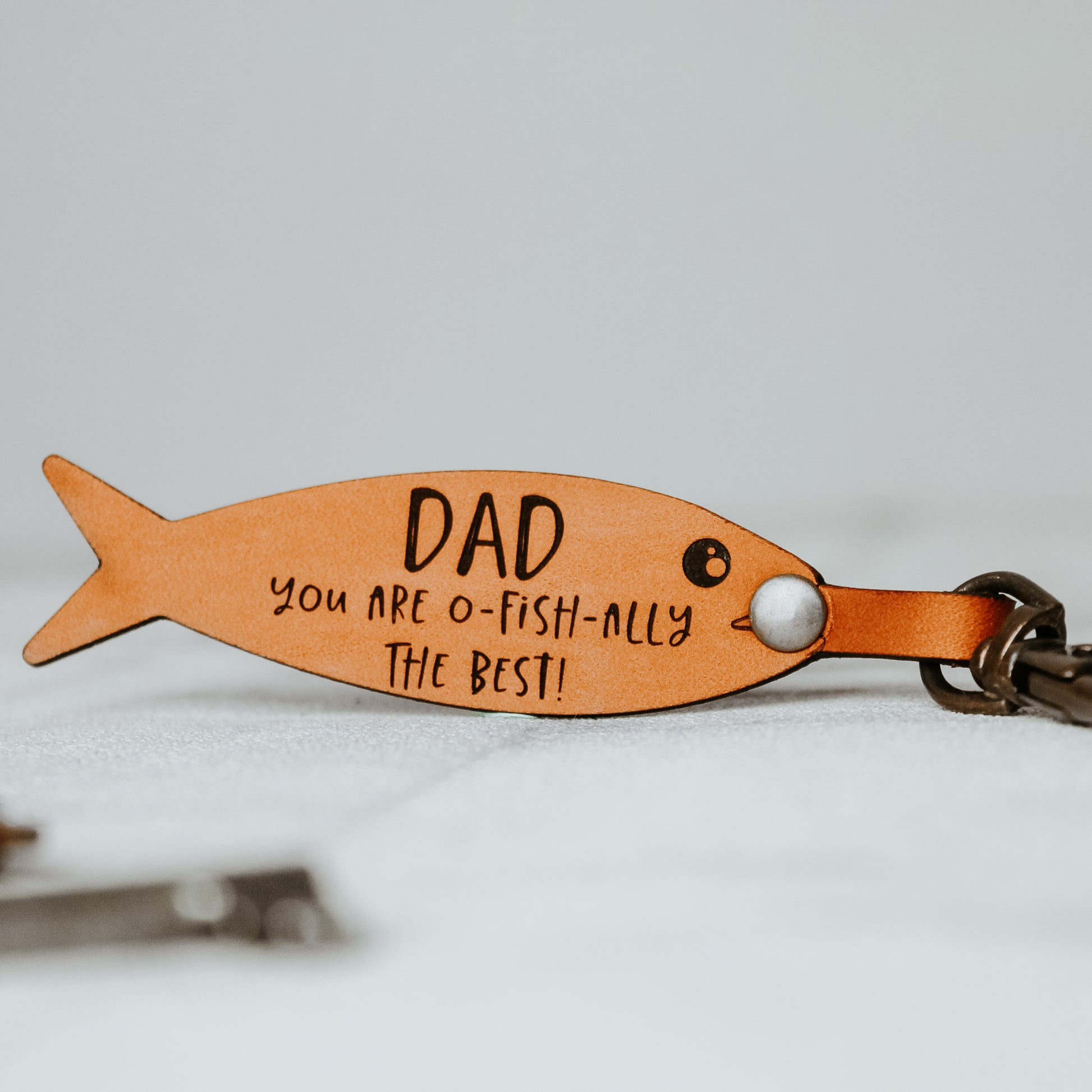 dad fishing keyring engraved on a fish shaped keyring in a whisky colour. 