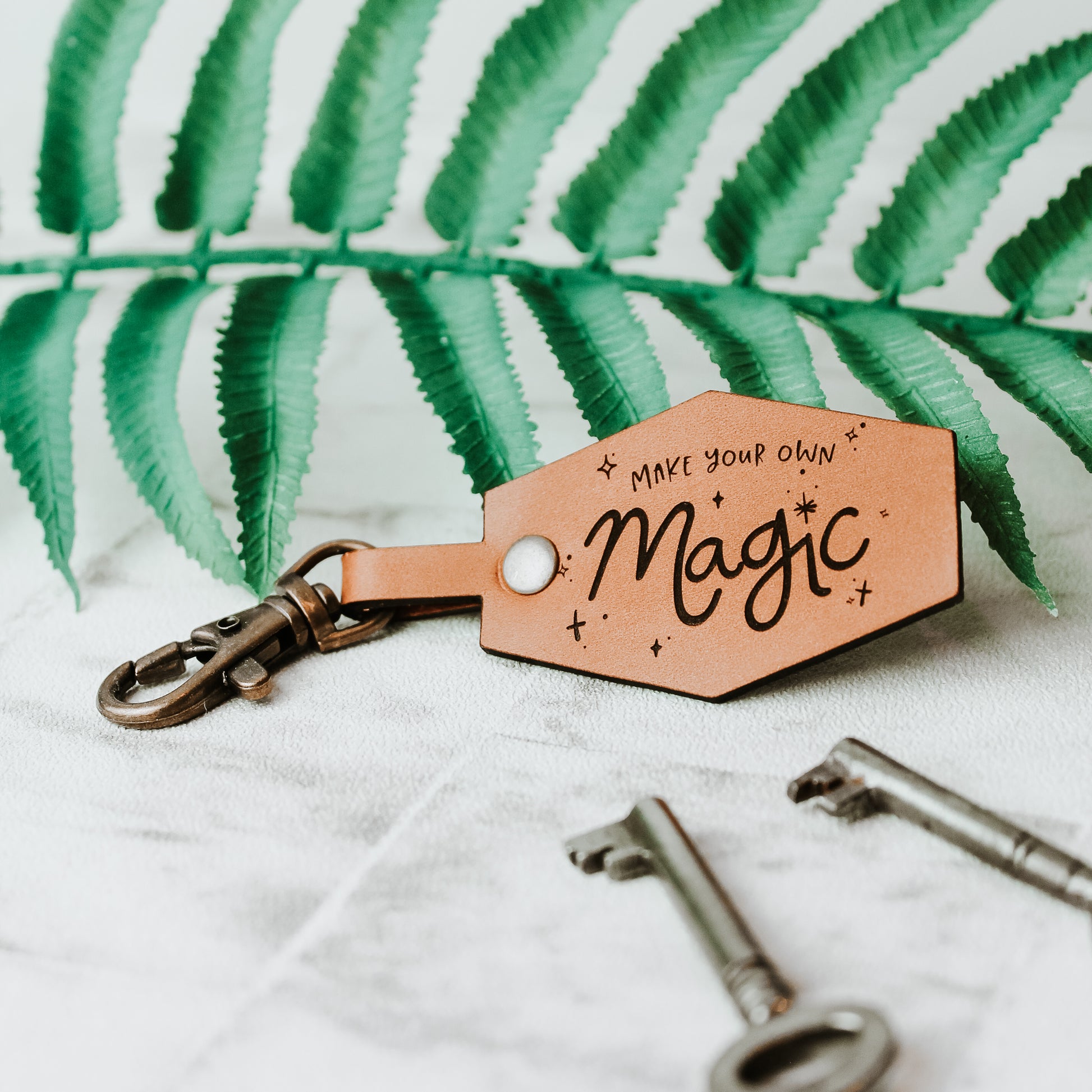 whisky coloured leather keyring engraved with the words: make your own magic. With celestial design around