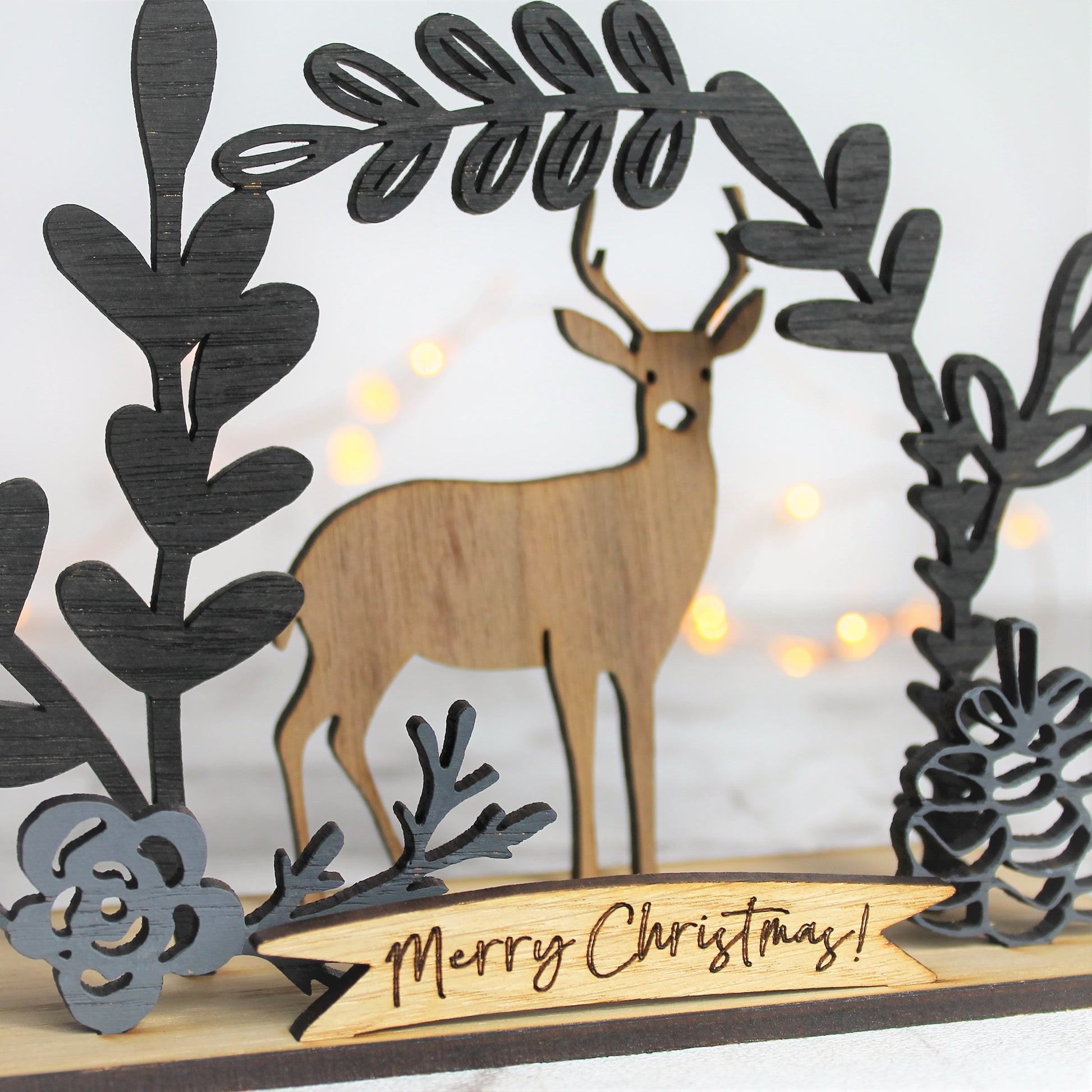 Merry christmas sign behing a winter scene with a deer and black floral flourishes 