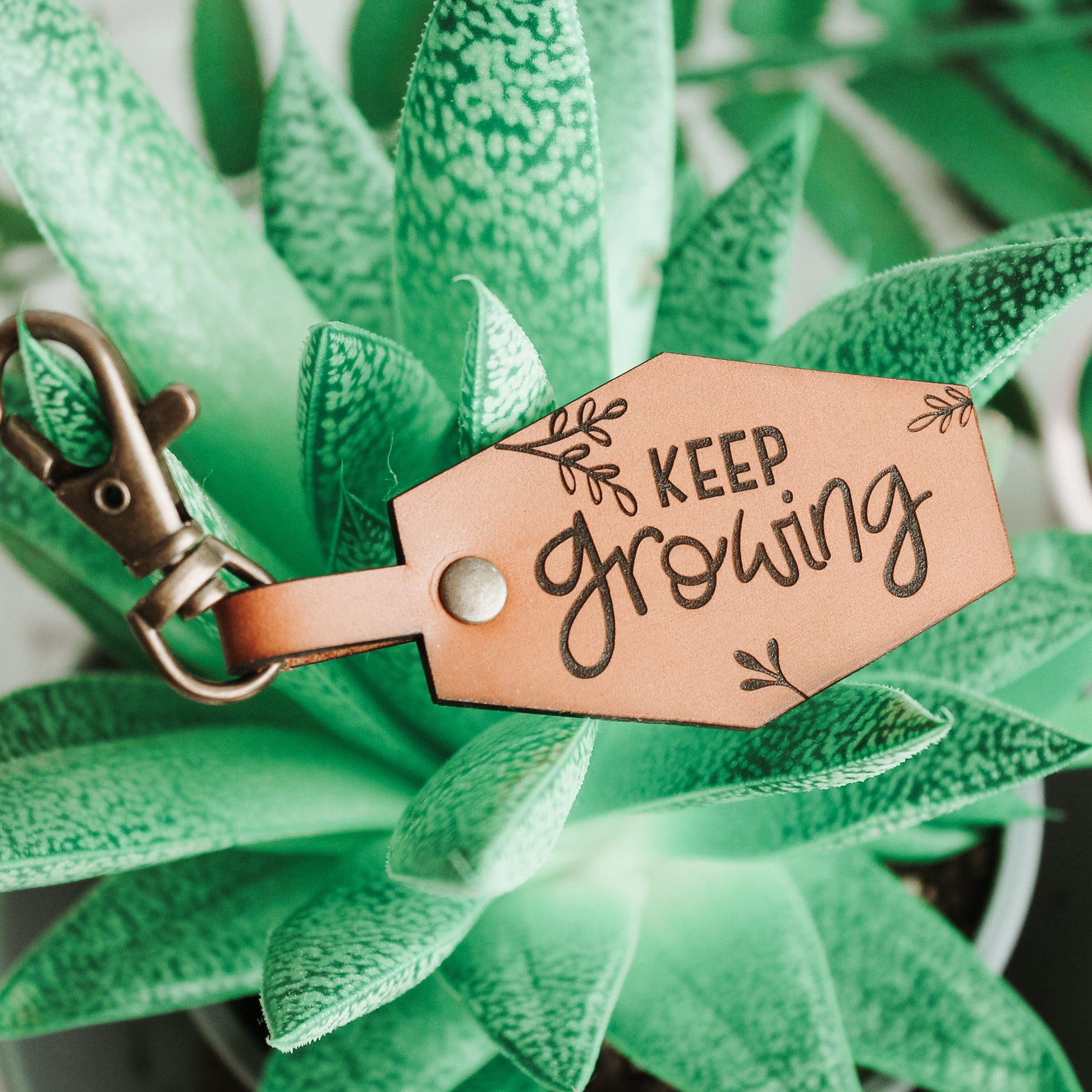plant lover motivational keyring with botanical flourishes and engraved with the words keep growing 