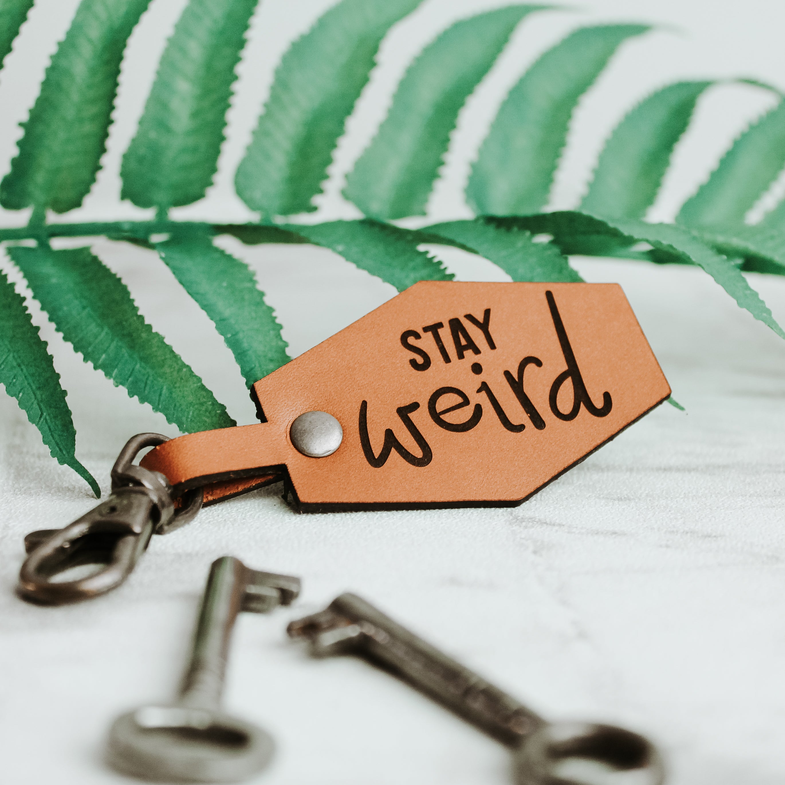 leather Keyring engraved with the words stay weird with swivel clasp