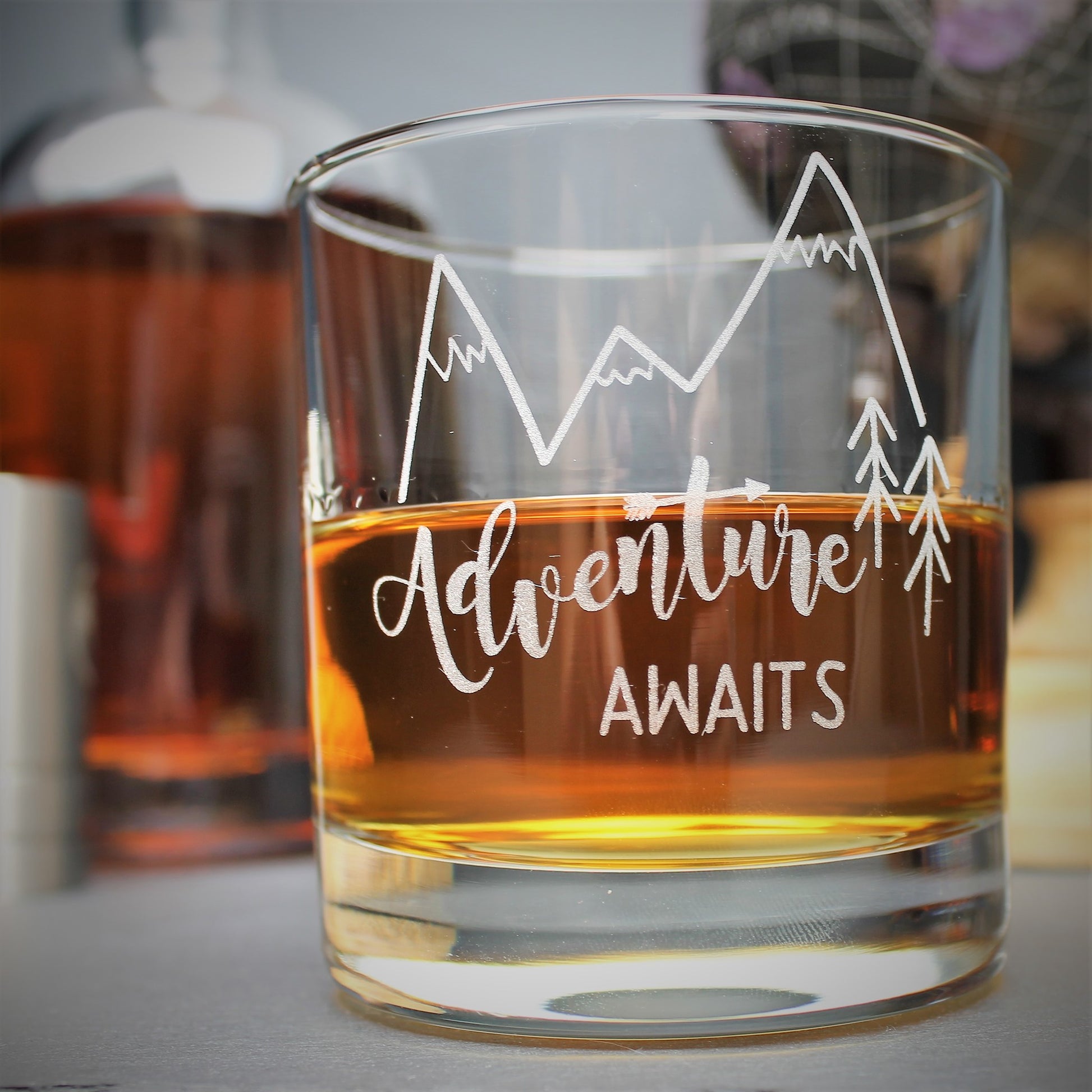 Engraved glass with mountain design and text that reads adventure awaits 