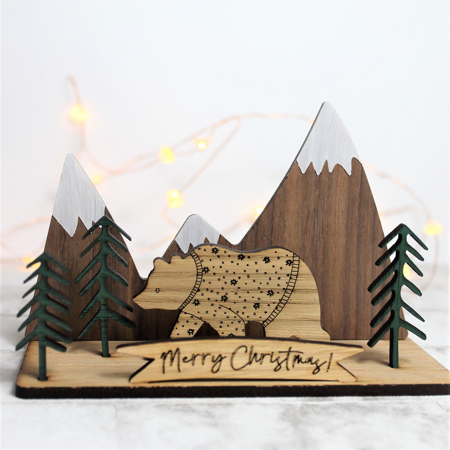 3d wooden ornament with mountain and forest scene, and a festive jumper bear