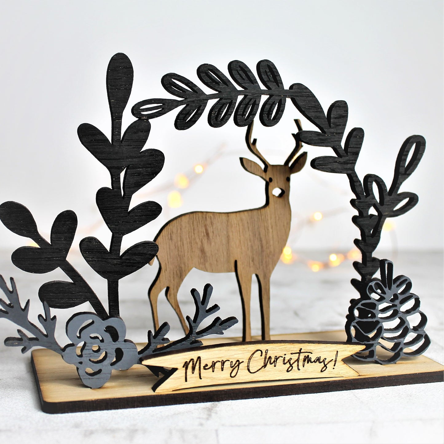 Woodland winter scene with deer silhouette and botanical leaves adorning the edges