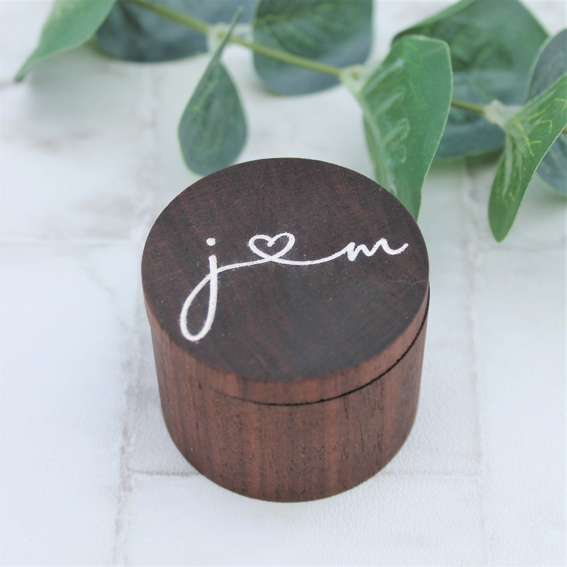 engraved wooden ring box with white initials in a calligraphy style