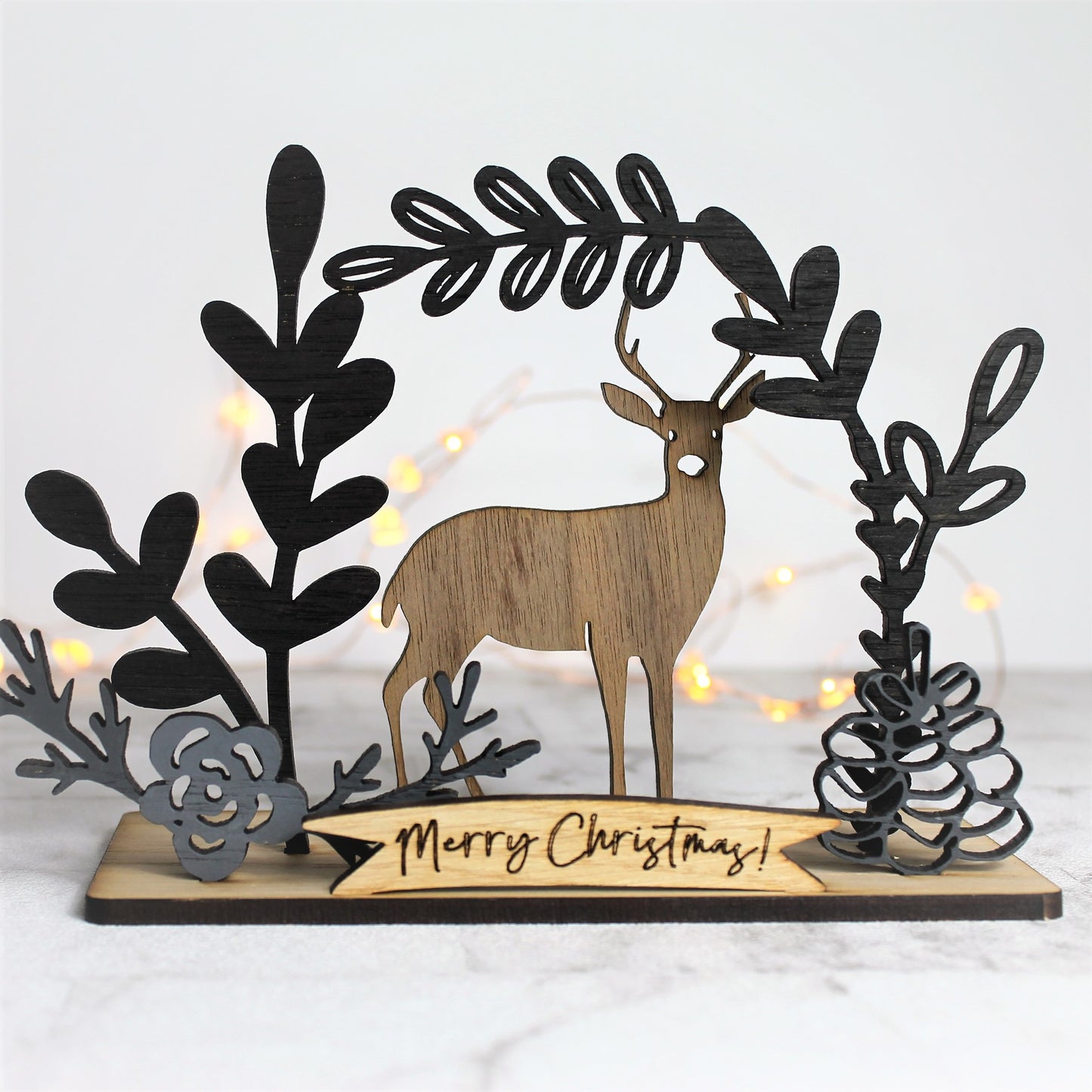 Wooden winter scene with deer and floral flourishes around the edges