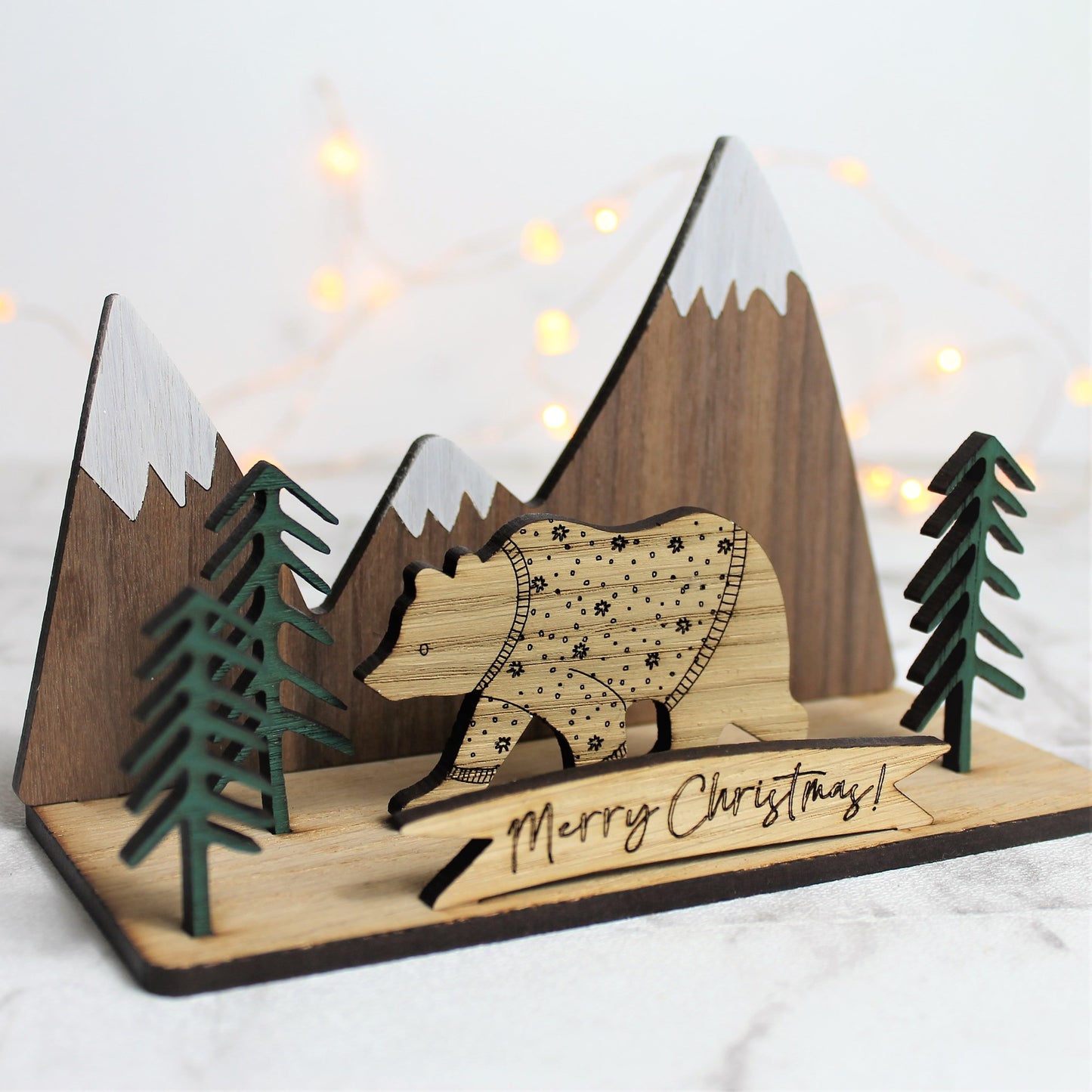 3d wooden ornament with mountain and forest scene, and a festive jumper bear